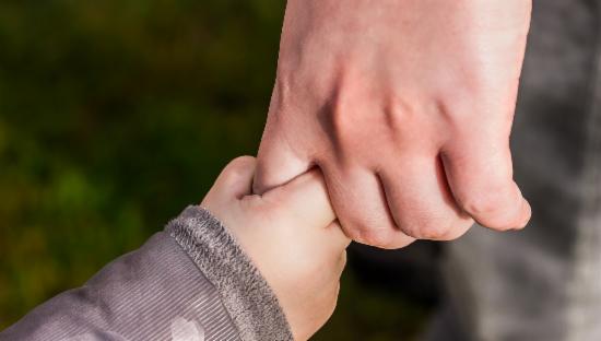 Barnehånd som holder en større hånd