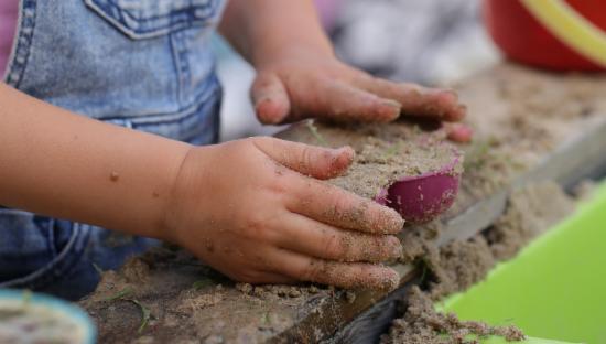 Barnehånd som leker med sand